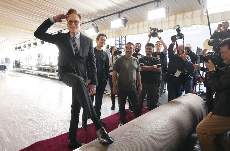 Conan O'Brien salutes photographers while rolling out the red carpet for the Oscars.